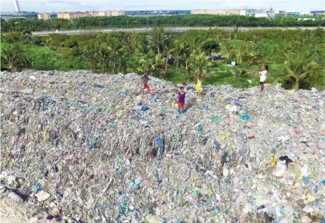  ?? (SUN.STAR FOTO/ALLAN CUIZON) ?? DUMPSITE. Dwarfed by a mountain of trash, young scavengers wait for the arrival of garbage trucks during the reopening of the Inayawan Sanitary landfill.