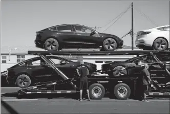  ?? PATRICK T. FALLON/BLOOMBERG ?? Workers unload Tesla Inc. Model 3 electric vehicles from a car carrier outside the company’s delivery center in Marina Del Rey, Calif.