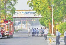  ?? PTI PHOTO ?? Firefighte­rs stand outside the LG Polymers factory as styrene vapours linger at a distance.