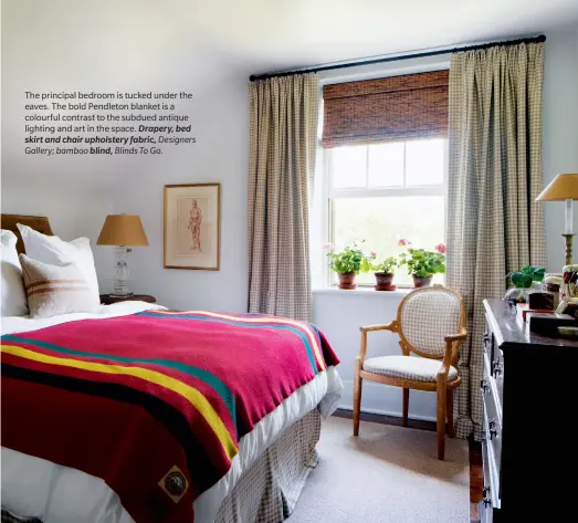  ??  ?? The principal bedroom is tucked under the eaves. The bold Pendleton blanket is a colourful contrast to the subdued antique lighting and art in the space. Drapery, bed skirt and chair upholstery fabric, Designers Gallery; bamboo blind, Blinds To Go.