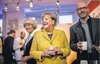  ?? AFP/ GETTY IMAGES ?? German Chancellor Angela Merkel, center, culture commission­er Monika Gruetters, left, and Christian Democrats secretary general Peter Tauber serve coffee to election workers Saturday.