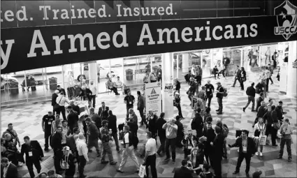  ?? AP PHOTO/JOHN LOCHER ?? In this Jan. 24, 2018, file photo, people walk through the hall outside of the SHOT Show gun show in Las Vegas.