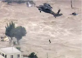  ?? TBS TV VIA THE ASSOCIATED PRESS ?? The man seen stranded next to the pole in the photo at left is rescued by a military helicopter crew in the photo at right. These are images from a video taken on Thursday in Joso, in Japan’s Ibaraki prefecture, by the Tokyo Broadcasti­ng System.