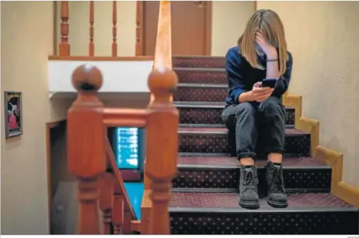 ?? UNICEF ?? Una niña mira su móvil sentada en las escaleras de su casa, durante el confinamie­nto.