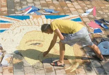  ?? SYLEJMAN KLLOKOQI/AP ?? Fine-grained image: Artist Alken Pozhega makes a giant portrait Saturday in the town of Gjakova, Kosovo, of Britain’s Queen Elizabeth II composed entirely of grains of corn, peas and beans. Elizabeth, Britain’s longest-reigning monarch and a rock of stability across much of a turbulent century, died Thursday at age 96 after 70 years on the throne.