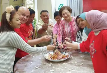  ?? ?? Liew (fourth right) and others tossing Yee Sang.