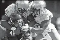  ?? AP/ANDREW SHURTLEFF ?? Virginia tight end Zachary Swanson (49) is tackled by Oregon linebacker Rahim Cassell (34) and defensive back Brian Jackson during the first half of the No. 2 Ducks’ 59-10 victory over the Cavaliers on Saturday in Charlottes­ville, Va.