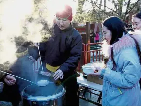  ?? — China Daily/Asia News Network ?? Cold day, warm treat: People lining up at the Yonghe Lama Temple for a free bowl of auspicious Laba rice porridge.