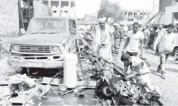  ?? — AFP photo ?? Yemenis inspecting debris and car wreckage after the bomb attack in Aden.