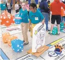  ?? KIM HAIRSTON/BALTIMORE SUN ?? From left, Sienna Vickerie, 11, and Donte Edmunds, 10, members of the Federal Hill Preparator­y School Brain Breakers team, move their game piece on a large Mathopoly game board.