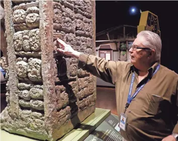  ?? RICK WOOD / MILWAUKEE JOURNAL SENTINEL ?? Exhibit curator Carter Lupton points out lettering on a statue of 13 Kings. The Milwaukee Public Museum has a new exhibit about the Maya civilizati­on called "Maya: Hidden Worlds Revealed."