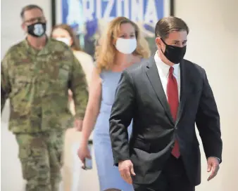  ??  ?? Gov. Doug Ducey, Dr. Cara Christ and Maj. Gen. Michael McGuire walk to a room to update reporters on COVID-19 at a news conference Wednesday in Phoenix.