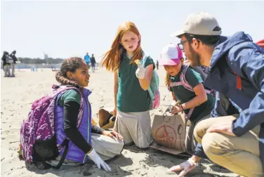  ?? Gabrielle Lurie / The Chronicle ?? Saiana Elkins (center) examines a piece of debris with Bella Luckey (left) and Helene Franks (right), alongside teacher Kevin Breakstone, during the 24th annual “Kids Ocean Day Adopt-a-Beach Cleanup.”