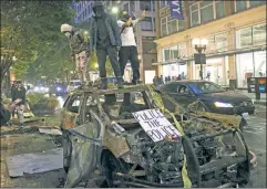  ??  ?? Lawless city: Anti-cop “protesters” atop a burnt-out vehicle in Seattle.