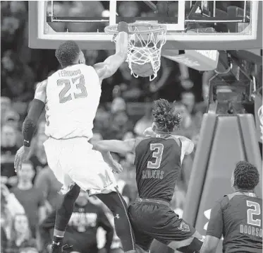  ?? NICK WASS/ASSOCIATED PRESS ?? Maryland center Bruno Fernando dunks over Rutgers guard Corey Sanders (3) and center Shaquille Doorson (2) during the first half of Saturday’s game. Fernando had 18 points and 16 rebounds to lead the Terps to victory.