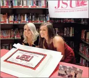  ?? / Kevin Myrick ?? Lizzie and Chloe Lee hold up a cake made in their honor at ceremonies on May 8 to make their decision to cheer with Jacksonvil­le State University.