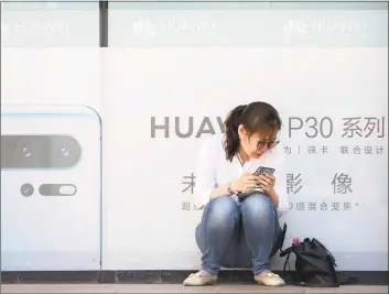  ?? Associated Press ?? A woman uses her smartphone outside of a shop selling Huawei products in Beijing. Chinese tech giant Huawei filed a motion in U.S. court Wednesday challengin­g the constituti­onality of a law that limits its sales of telecom equipment, the latest action in an ongoing clash with the U.S. government.