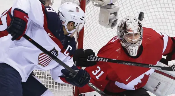  ?? RICHARD LAUTENS/TORONTO STAR ?? CLOSE CALL Team USA captain Zach Parise and Canadian goalie Carey Price track a bouncing puck in the Winter Olympics semifinal in Sochi. Canada won 1-0.