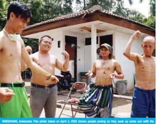  ??  ?? TANGERANG, Indonesia: This photo taken on April 3, 2020 shows people posing as they soak up some sun with the belief that the sun can boost their body immunity amid concerns over the coronaviru­s outbreak.