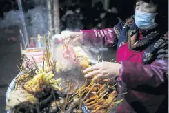  ??  ?? A vendor sells snacks outside a bar on a street in Wuhan.