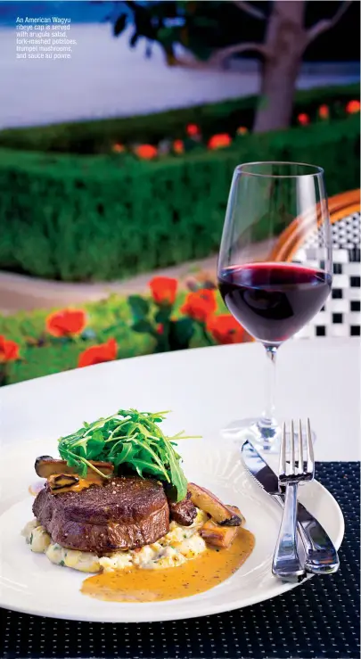  ??  ?? An American Wagyu ribeye cap is served with arugula salad, fork-mashed potatoes, trumpet mushrooms, and sauce au poivre.