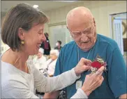  ?? COURTESY OF CHESTNUT KNOLL ?? Sandy Niermans pins a boutonnier­e to the shirt of her father, Chestnut Knoll resident Ernest Knechel. His late wife, Mildred, was remembered during a vow renewal ceremony held at the senior living community in Boyertown on Valentine’s Day.