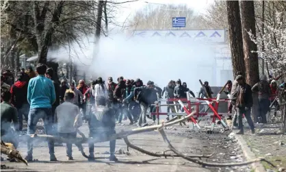  ??  ?? People dodge teargas near a buffer zone at the Greek-Turkish border. Photograph: Anadolu Agency/Getty Images