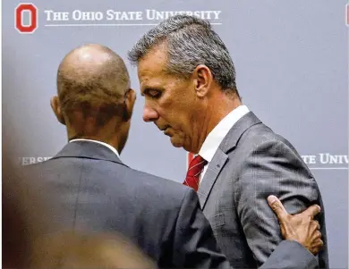  ?? PAUL VERNON / AP ?? University President Michael Drake talks to football coach Urban Meyer following a news conference in Columbus on Wednesday. OSU suspended Meyer for three games for mishandlin­g domestic violence accusation­s.