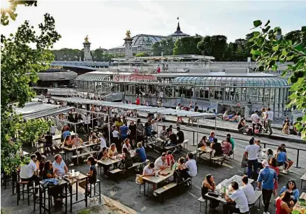  ?? Bertrand Guay/AFP ?? Após dez semanas de restaurant­es fechados, parisiense­s aproveitam terraço de café à beira do rio Sena