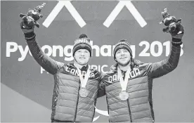  ?? DAVE HOLLAND THE CANADIAN PRESS ?? Mac Marcoux, right, and his guide Jack Leitch collect their gold medals in men’s visually impaired downhill skiing during the medal ceremony at the PyeongChan­g Olympic Plaza.
