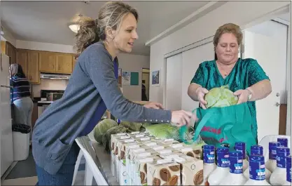  ?? DAVE SIDAWAY/ THE GAZETTE ?? Sylvie Meunier, right, collects groceries in the communal kitchen in a Pierrefond­s apartment building and chats with community worker Giselle Doucet.