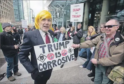  ?? CP PHOTO ?? A man dressed as U.S. President Donald Trump jokes with protesters outside the official opening of the Trump Internatio­nal Hotel and Tower in Vancouver, B.C., on Tuesday.