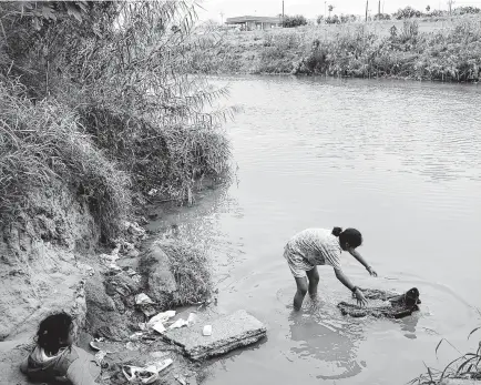  ?? Bob Owen / Staff photograph­er ?? Maria Rodriguez Hernandez, a 12-year-old migrant from Oaxaca, Mexico, washes clothes in the Rio Grande with young friend Diyana from Honduras at the refugee camp in Matamoros, Mexico.