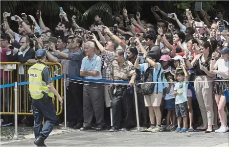  ??  ?? Huge draw: Curious onlookers waiting for the departure of Trump’s motorcade from the Presidenti­al Palace in Singapore.