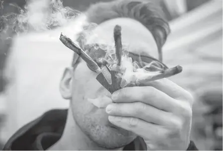  ?? DARRYL DYCK, THE CANADIAN PRESS ?? Brandon Bartelds smokes three joints at once while attending the 4-20 annual marijuana celebratio­n in Vancouver. North Shore Search and Rescue is making sure hikers are aware of the dangers of experiment­ing with drugs in rough terrain.