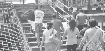  ??  ?? Medical personnel carry a patient on a stretcher gingerly up the stairs to the terminal following a stint at Sibu Hospital.