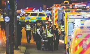  ?? DANIEL SORABJI / AFP / GETTY IMAGES ?? Police and emergency workers help a person injured in a terror attack on London Bridge on June 3, 2017. An inquest into the van-and-stabbing attack that left eight dead heard of the bravery of some who were killed and injured in the attack.