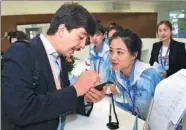  ?? LI ZIHENG / XINHUA ?? A reporter from Tajikistan asks a volunteer questions at the opening of the media center for the Shanghai Cooperatio­n Organizati­on Summit in Qingdao, Shandong province, on Wednesday.