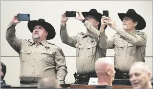  ?? ?? BELOW: La Paz County Sheriff’s Office Chief Deputy David Gray (left), Navajo County Sheriff’s Office Chief Deputy Brian Swanty and Graham County Sheriff’s Office Undersheri­ff Dennis Newman take cell phone photos and videos before the start of Thursday’s U.S. House Judiciary Committee hearing.