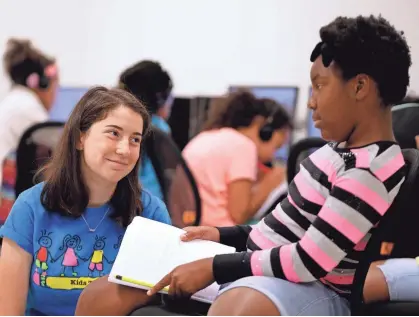  ?? RICK WOOD / MILWAUKEE JOURNAL SENTINEL ?? Katie Eder (left), a senior in high school, smiles at an answer from Keisha Walton, 10, as Eder teaches Kids Tales, a summer camp workshop on creative writing for children at the COA Youth and Family Center. See more photos at jsonline.com/news.