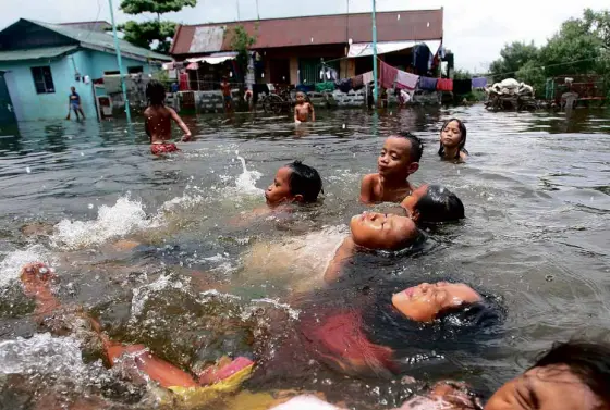  ??  ?? CHILDREN swim in the flooded streets of Obando, Bulacan, a town trying to deal with floods that are regular occurrence­s because of high tide.