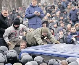  ?? PHOTOS: SERGEI CHUZAVKOV/AFP/GETTY IMAGES ?? Supporters of former Georgian president Mikheil Saakashvil­i attempt to release him from a police van after he was arrested in Kyiv, Ukraine, on Tuesday. The politician also served as governor of Ukraine’s Odessa region.