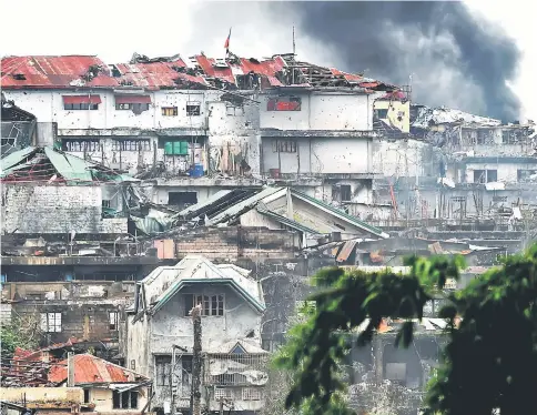  ?? — AFP photo ?? This file photo shows black smoke billowing from a burning house after an an aerial strike by Philippine airforce attack helicopter­s targeting Islamist militants in Marawi.