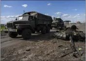  ?? BERNAT ARMANGUE — THE ASSOCIATED PRESS ?? Ukrainian army vehicles drive past the remains of a Russian tank in north Kharkiv, east Ukraine, on Friday.