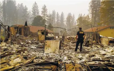  ?? AP PHOTO/JOHN LOCHER ?? A member of the Sacramento County coroner’s office looks for human remains Monday in the rubble of a house burned in the Camp Fire in Paradise, Calif.