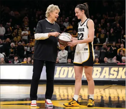  ?? PHOTOS BY MATTHEW PUTNEY — THE ASSOCIATED PRESS ?? Iowa coach Lisa Bluder presents guard Caitlin Clark (22) with a commemorat­ive basketball after the team’s game against Michigan on Thursday, in Iowa City, Iowa. Clark broke the NCAA women’s career scoring record.