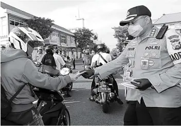  ?? GUSLAN GUMILANG/JAWA POS ?? DIPAKAI YA: Kombespol Johnny Eddizon Isir membagikan masker kepada pengemudi di Jalan Sikatan depan Mapolresta­bes Surabaya kemarin.