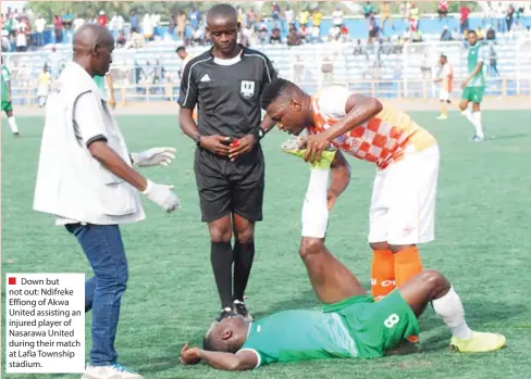  ??  ?? Down but not out: Ndifreke Effiong of Akwa United assisting an injured player of Nasarawa United during their match at Lafia Township stadium.