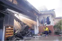  ?? MARCIO JOSE SANCHEZ/ASSOCIATED PRESS ?? Calib Willis of the Los Angeles County Fire Department hoses down a smoldering residence destroyed by a wildfire on Friday in Santa Clarita, near Los Angeles, Calif.