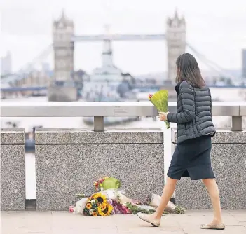  ??  ?? Passanten legen auf der London Bridge zum Gedenken an die Toten und Verletzten Blumen nieder.
